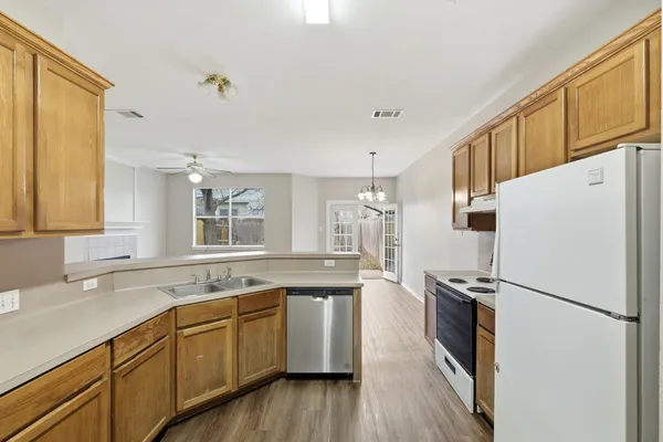 a kitchen with granite countertop a sink a refrigerator a stove and wooden floors