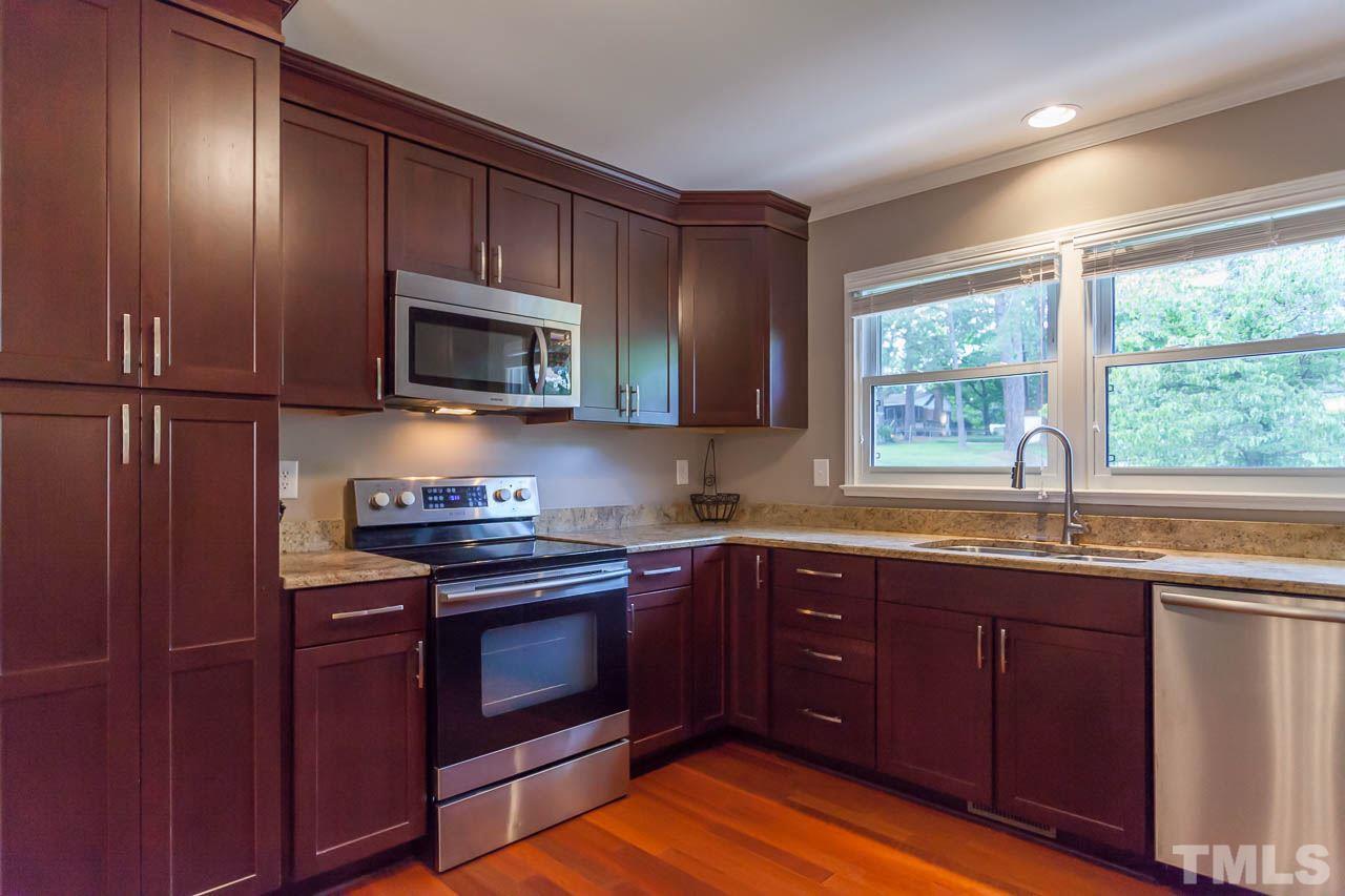 3145 Merrianne Drive Raleigh, NC 27607 - Photo 9 of 25 a kitchen with stainless steel appliances granite countertop wooden cabinets and a stove top oven