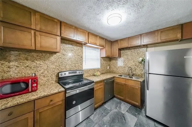 a kitchen with stainless steel appliances granite countertop a stove a refrigerator and a sink