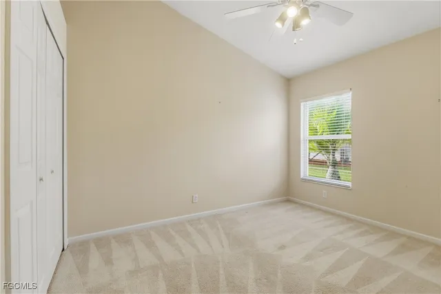 an empty room with a chandelier fan and closet area