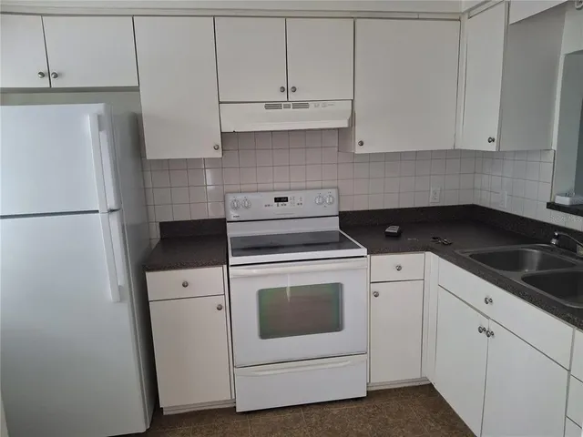 a kitchen with white cabinets and white appliances