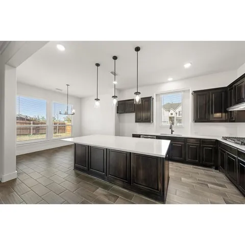 a kitchen with stainless steel appliances kitchen island granite countertop a refrigerator a sink dishwasher and a stove with wooden floor