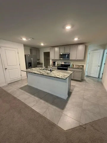 a kitchen with stainless steel appliances granite countertop a sink a stove a refrigerator a microwave oven and a refrigerator