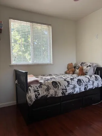 a bedroom with a bed wooden floor and a window