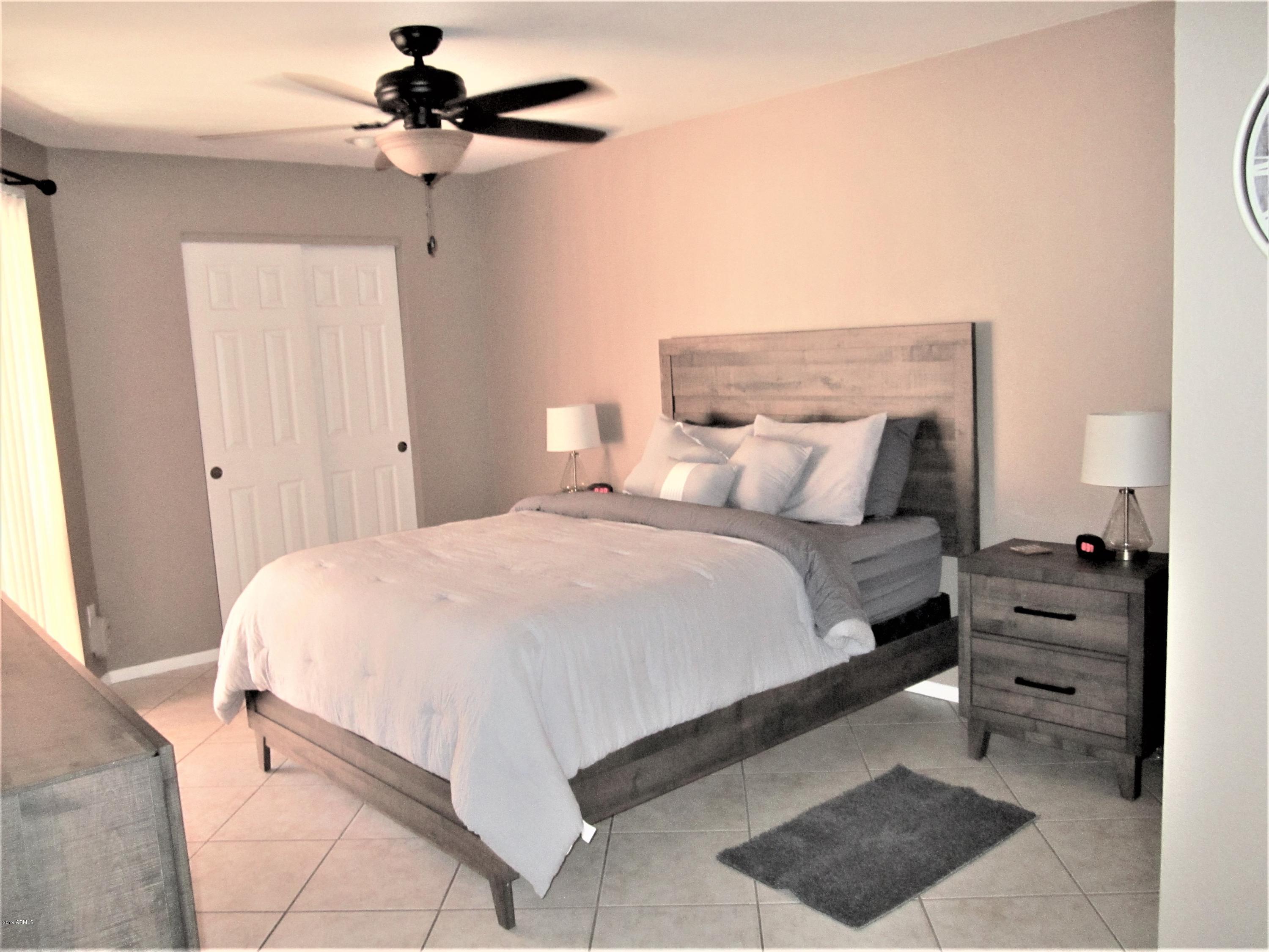 4303 East Cactus Road, Unit 116 Phoenix, AZ 85032 - Photo 12 of 35 a bedroom with a bed and a chandelier
