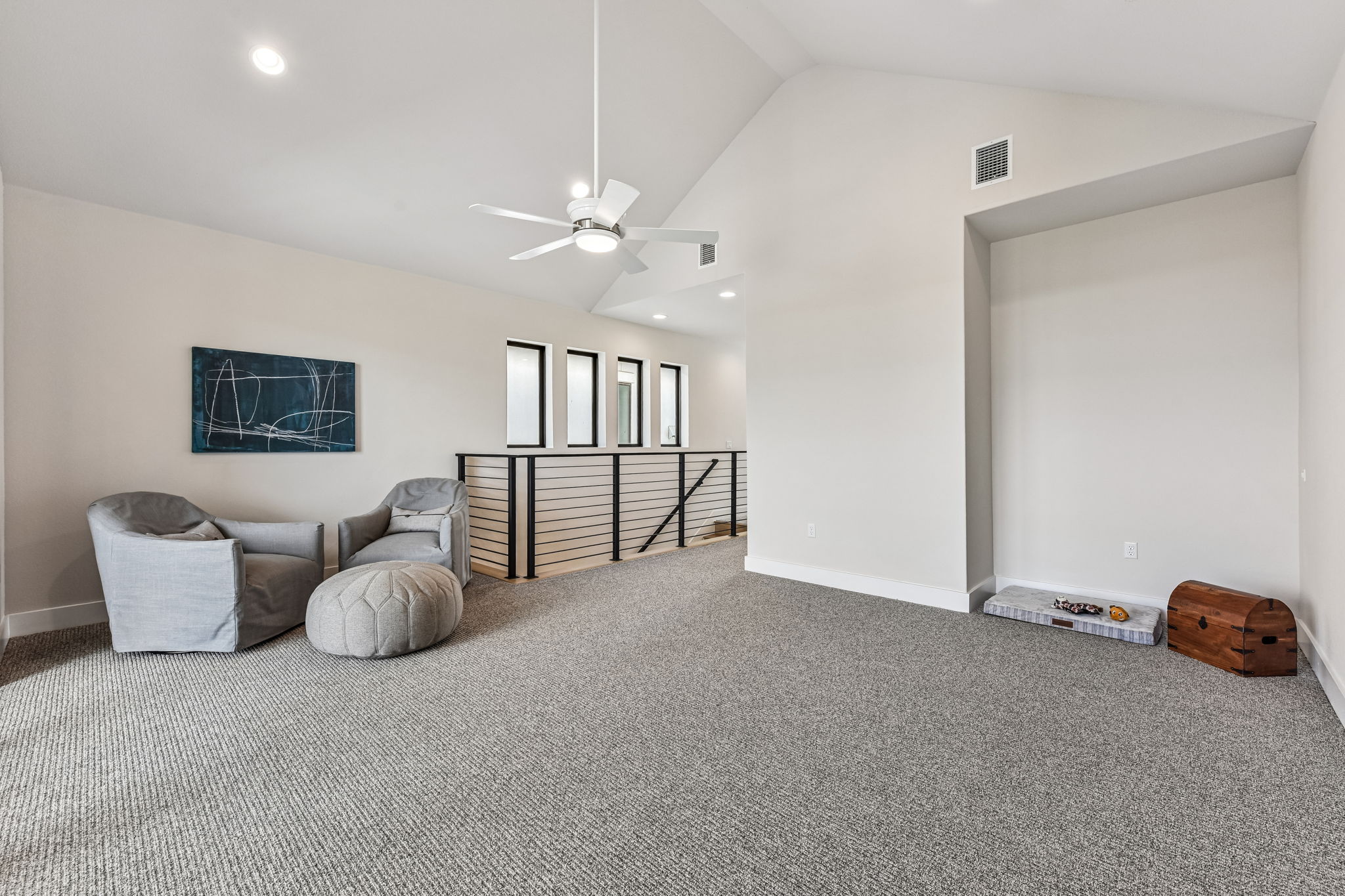 9033 Cattle Baron Path Austin, TX 78747 - Photo 26 of 40 An airy loft area features a vaulted ceiling and a clean, contemporary aesthetic with a sleek railing overlooking the floor below.