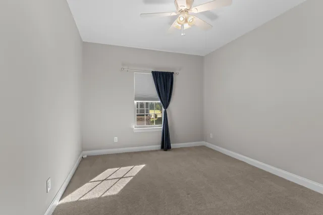 an empty room with a chandelier fan and windows