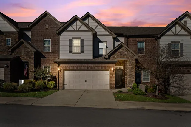 a front view of a house with a garden and trees