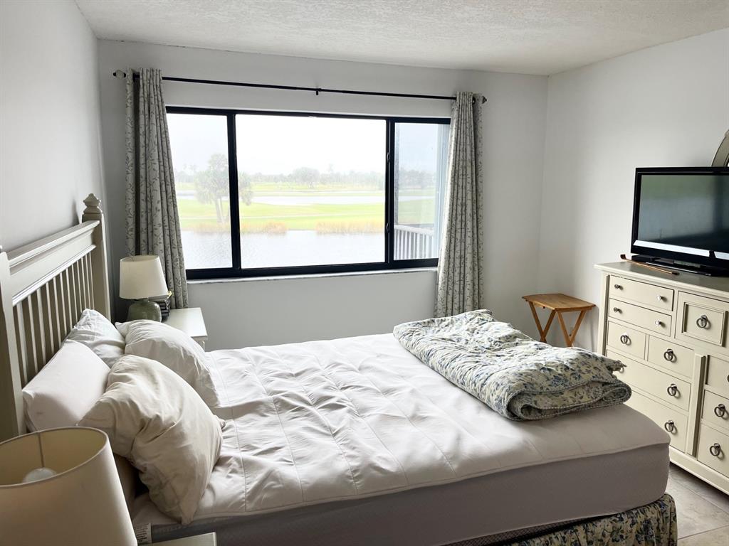 40 Northeast Plantation Road, Unit 208 Stuart, FL 34996 - Photo 30 of 38 a bedroom with a bed and a flat screen tv