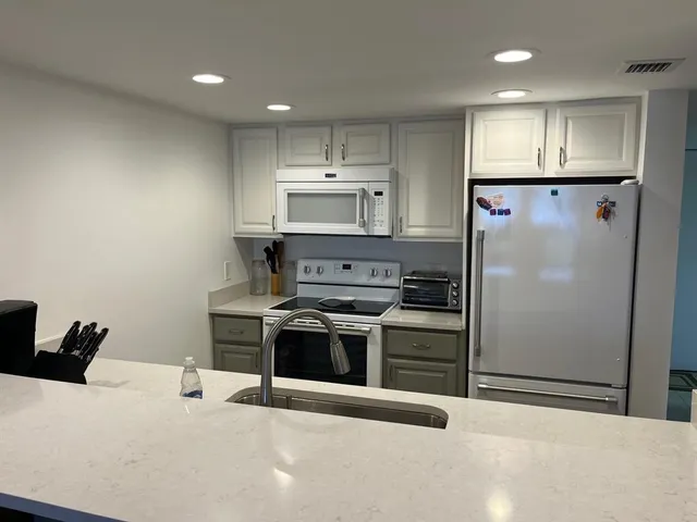 a kitchen with stainless steel appliances granite countertop a refrigerator a stove and a sink