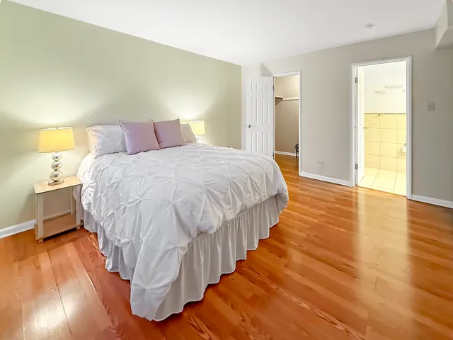 a spacious bedroom with a bed and wooden floor
