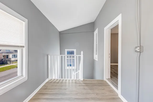 a view of a hallway with wooden floor and a window