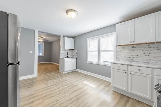 a kitchen with white cabinets and wooden floor