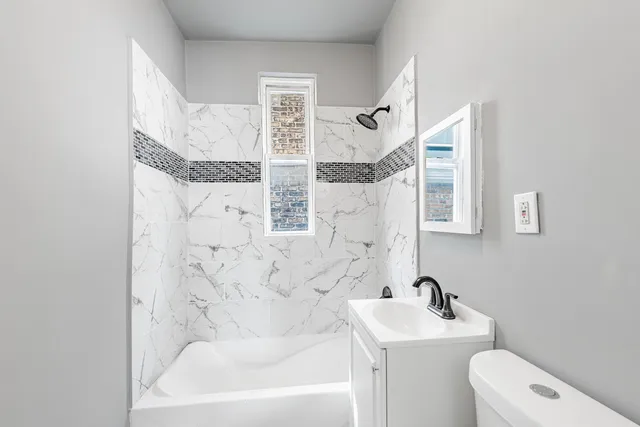 a bathroom with a granite countertop sink mirror vanity and toilet