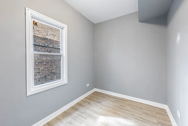 a view of an empty room with window and wooden floor