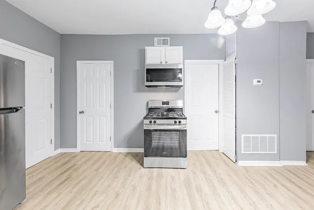 a kitchen with stainless steel appliances a stove top oven a refrigerator a sink and dishwasher with wooden floor