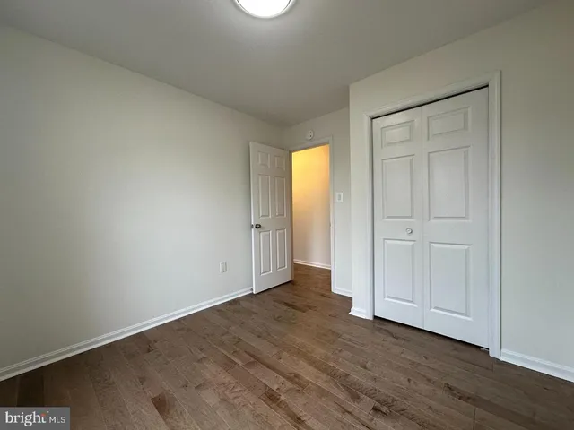 a view of an empty room with wooden floor and closet