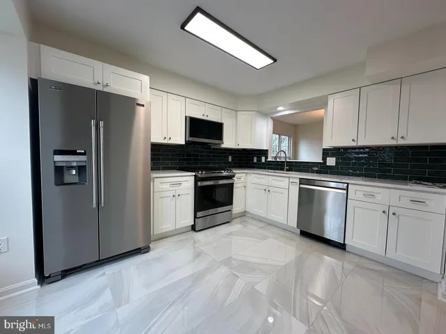a kitchen with granite countertop white cabinets and stainless steel appliances