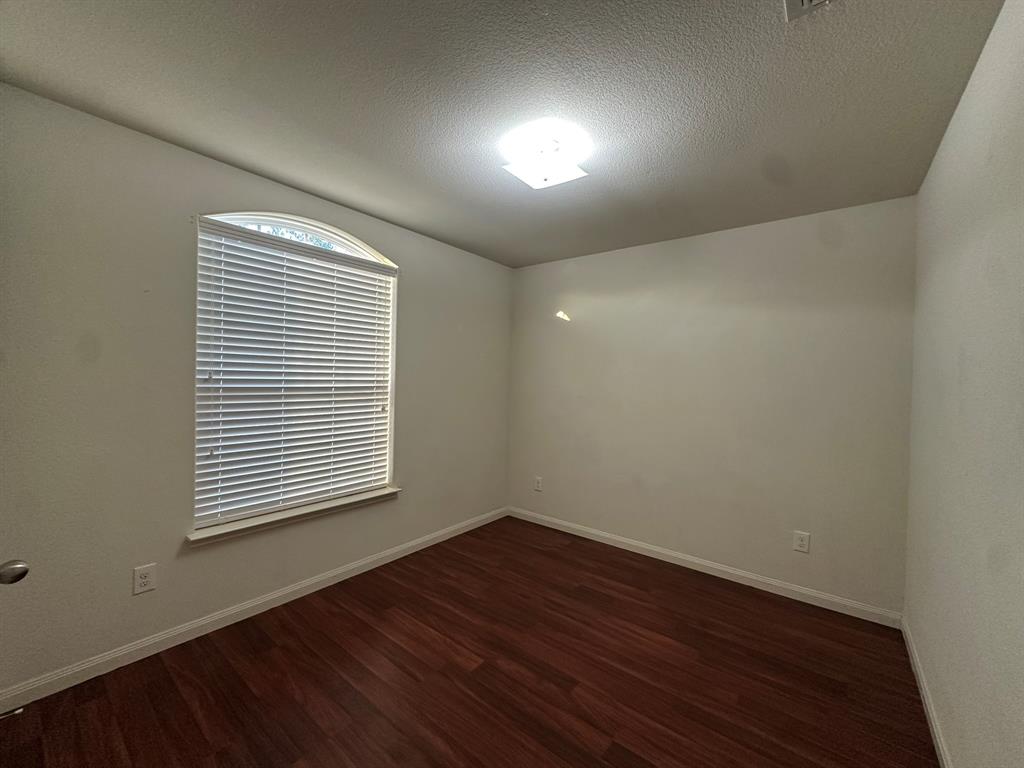 1818 Clegg Street Howe, TX 75459 - Photo 4 of 34 Bedroom featuring dark wood-finish flooring, light neutral wall paint, and a window with an arched transom