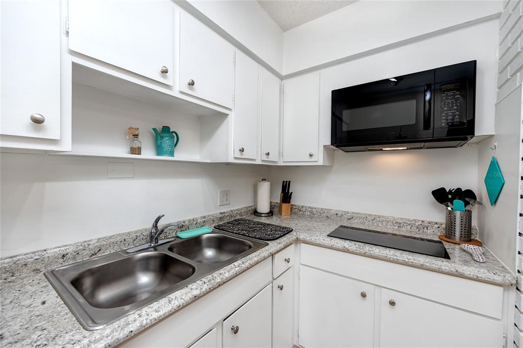 5596 100th Way North St. Petersburg, FL 33708 - Photo 50 of 67 a kitchen with stainless steel appliances granite countertop a sink a microwave and cabinets