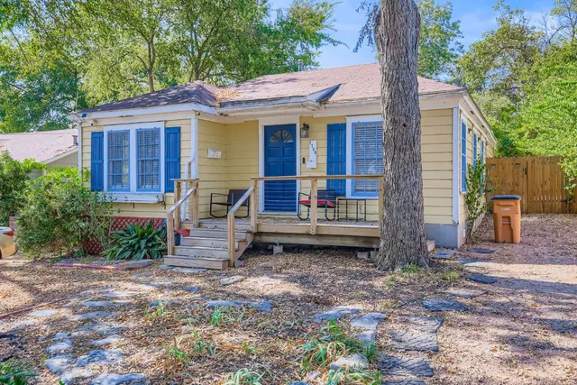 a view of a house with a yard and large tree