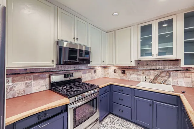 a kitchen with granite countertop cabinets and steel stove top oven