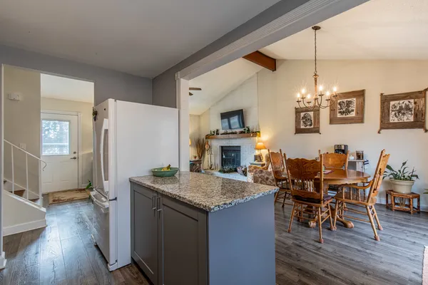 a open kitchen with stainless steel appliances granite countertop a stove top oven a refrigerator a dining table and chairs with wooden floor