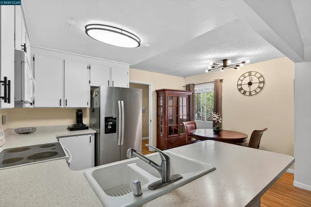 a kitchen with stainless steel appliances granite countertop a sink dishwasher and a refrigerator with wooden floor