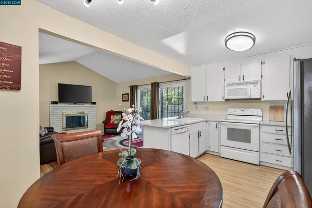 a kitchen with a sink dishwasher stove and white cabinets with wooden floor