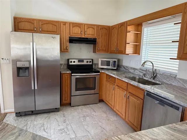 a kitchen with stainless steel appliances granite countertop a refrigerator stove and sink