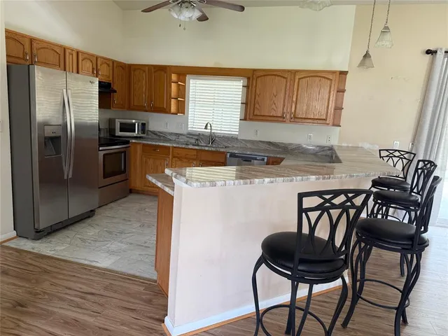 a kitchen with stainless steel appliances granite countertop a stove a refrigerator a sink a dining table and chairs with wooden floor