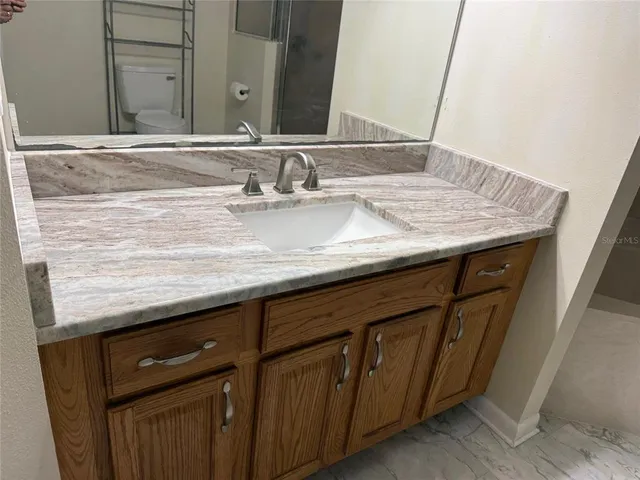 a sink with a granite countertop sink and a mirror