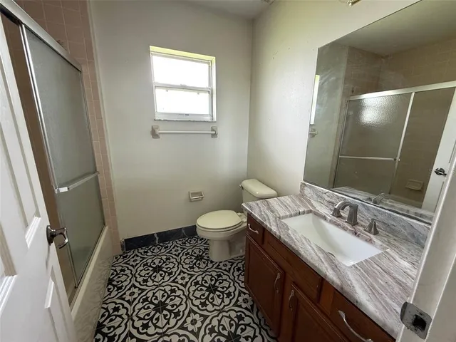 a bathroom with a granite countertop sink toilet a mirror and shower