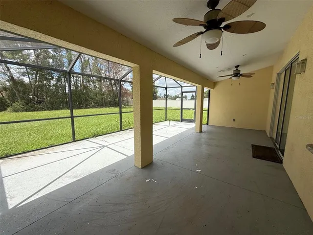 a view of an empty room and a ceiling fan and window