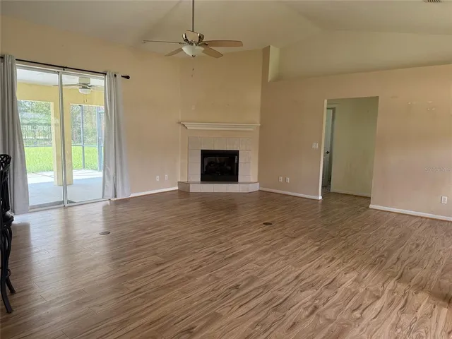 an empty room with wooden floor fireplace and windows
