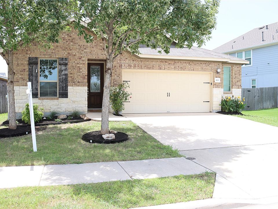View of front of home with concrete driveway, stone siding, brick siding, and a garage