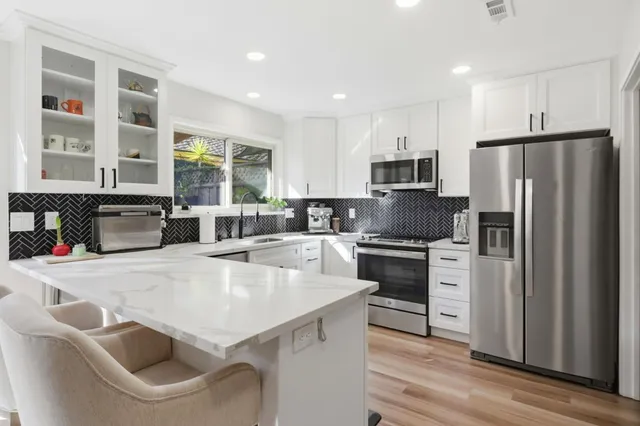 a kitchen with a sink dishwasher a stove and white cabinets with wooden floor