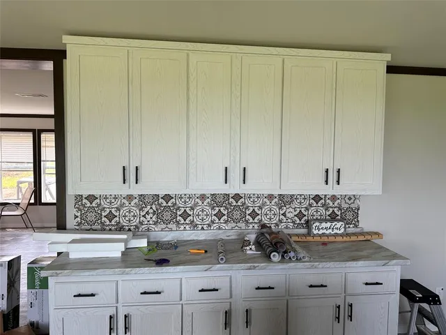 a kitchen with white cabinets and sink