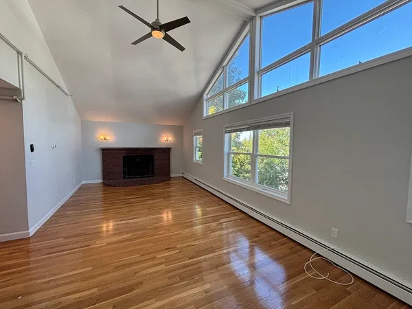 a view of empty room with wooden floor and fan