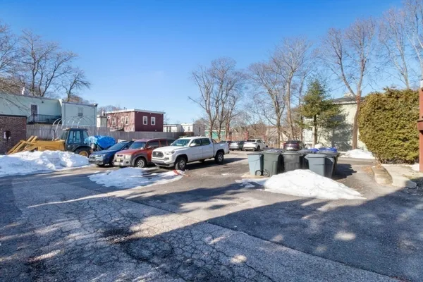 a view of road with card parked on side and retail shops