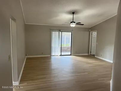 an empty room with wooden floor chandelier and windows