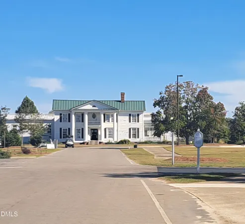 a view of a white house with a big yard and large trees
