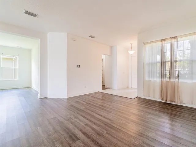 a view of an empty room with wooden floor and a window