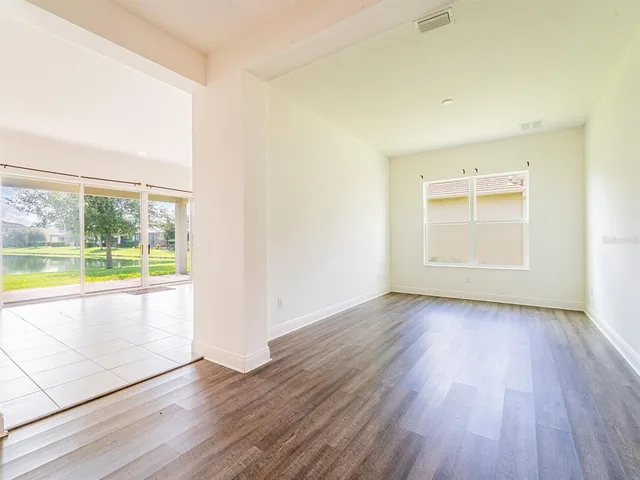 an empty room with wooden floor and windows