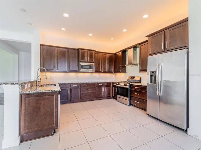 a kitchen with granite countertop a refrigerator and a stove top oven