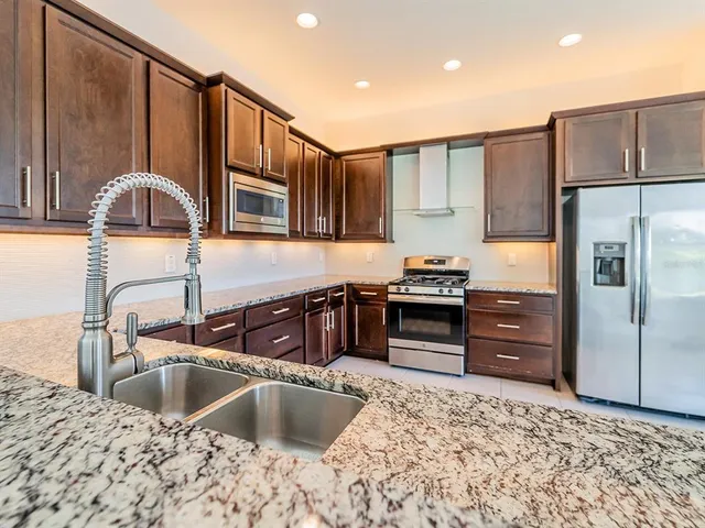 a kitchen with stainless steel appliances granite countertop a sink stove and refrigerator