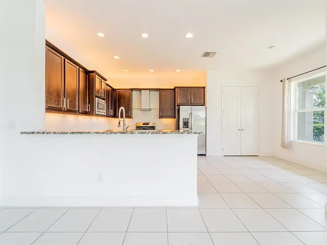 a view of kitchen with stainless steel appliances granite countertop a refrigerator a sink and a cabinets