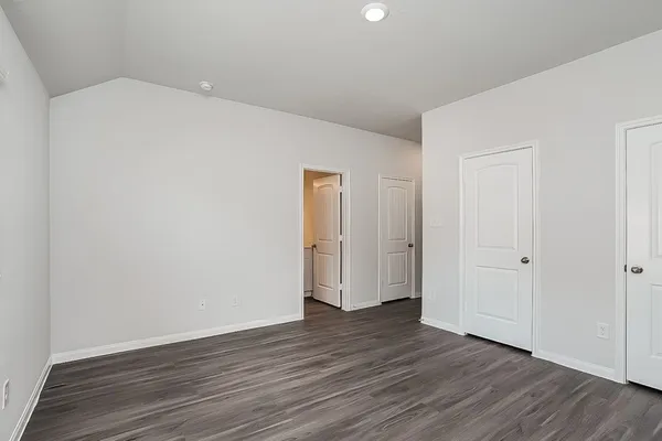 a view of an empty room with wooden floor and closet