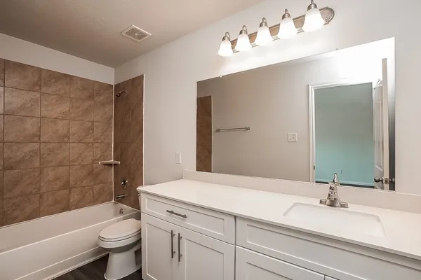 a bathroom with a bathtub shower sink vanity mirror and toilet