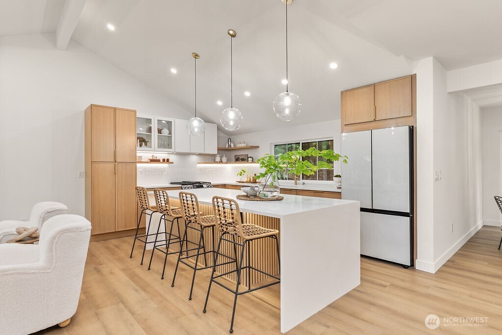 19433 Southeast 128th Street Renton, WA 98059 - Photo 18 of 40 a kitchen with stainless steel appliances granite countertop a refrigerator a stove a sink dishwasher a dining table and chairs with wooden floor